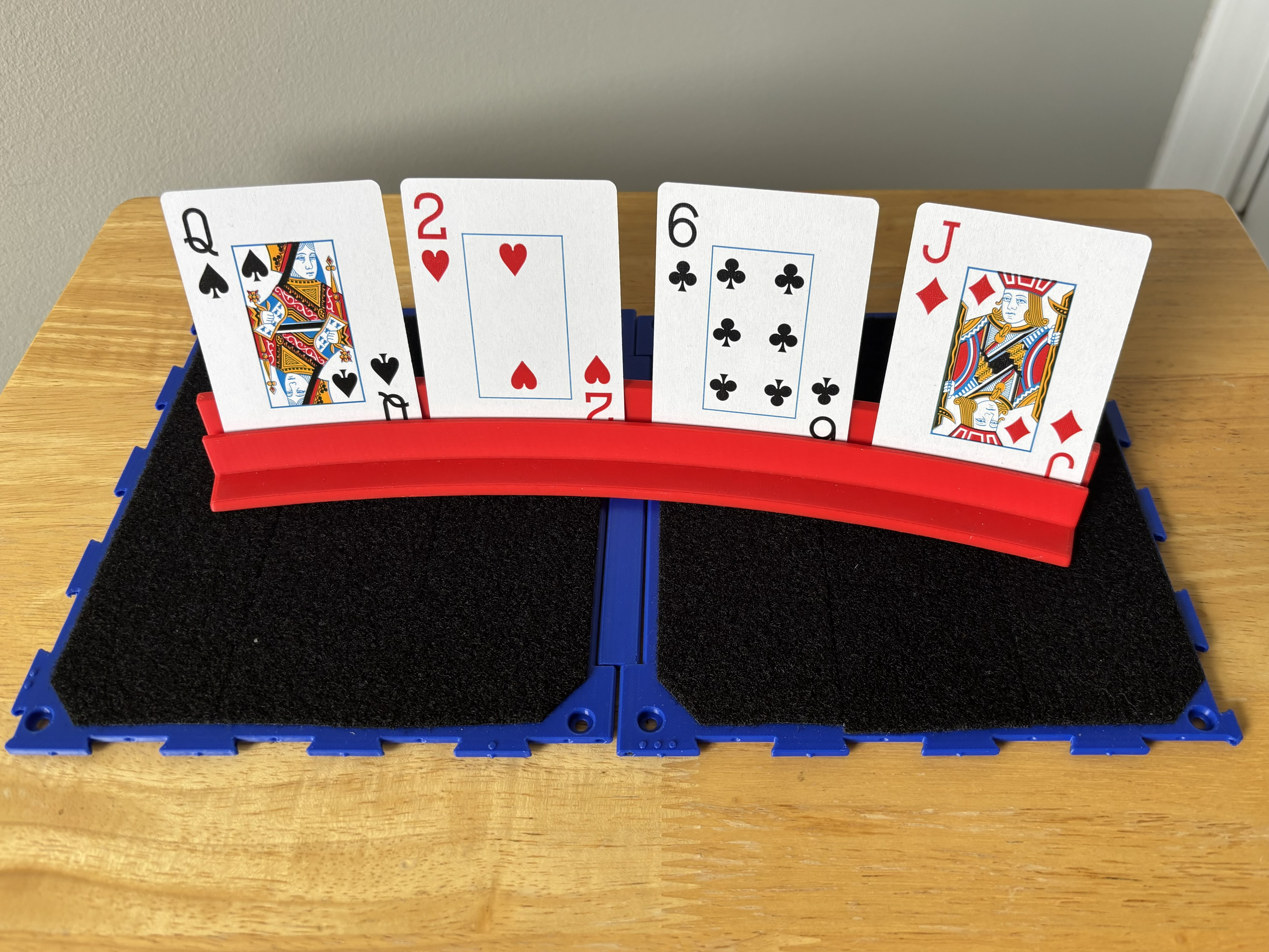 A Connect Board resting on a table and being used to position and restrain a 3D printed playing card holder with 4 playing cards inside.
