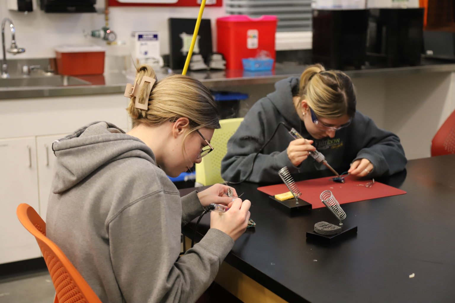 Two student working on soldering assistive switches