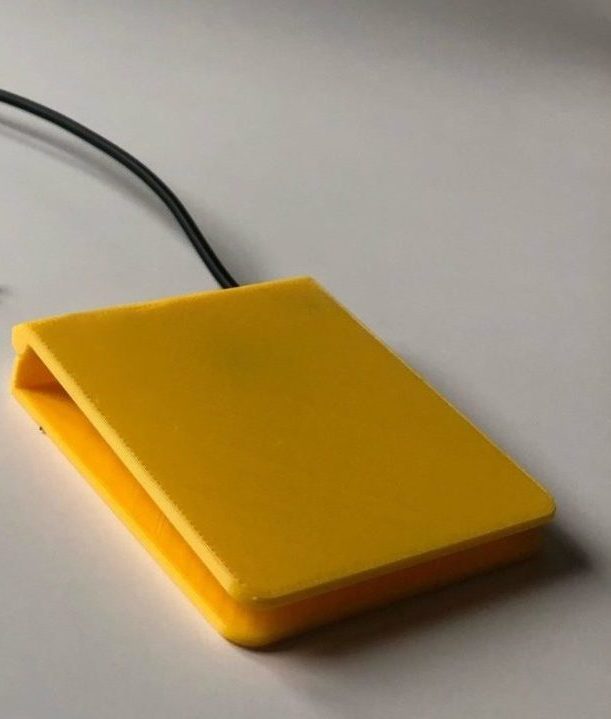 A yellow 3d printed low profile assistive switch with a mono jack end.