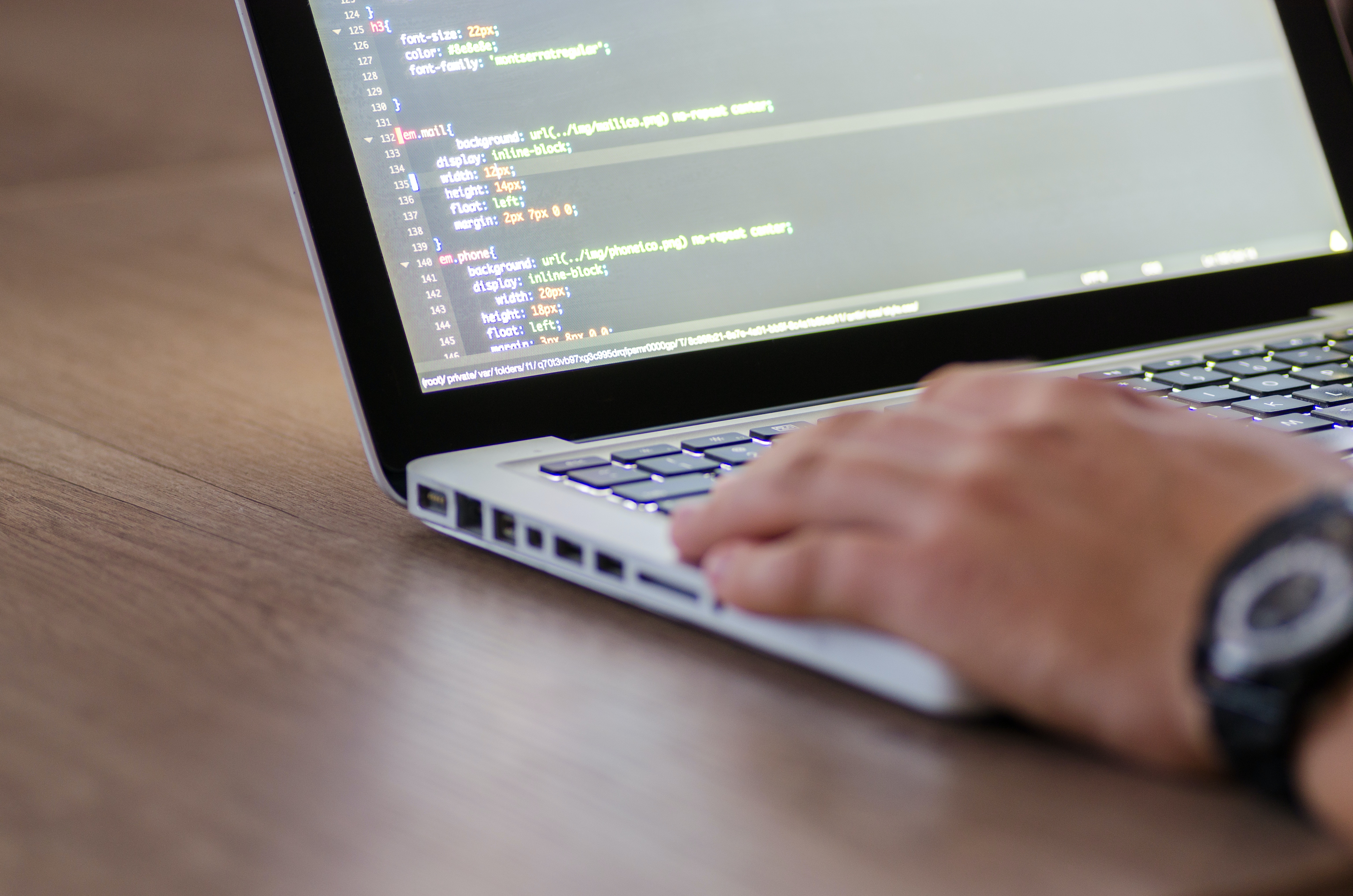 A person typing code on a laptop.