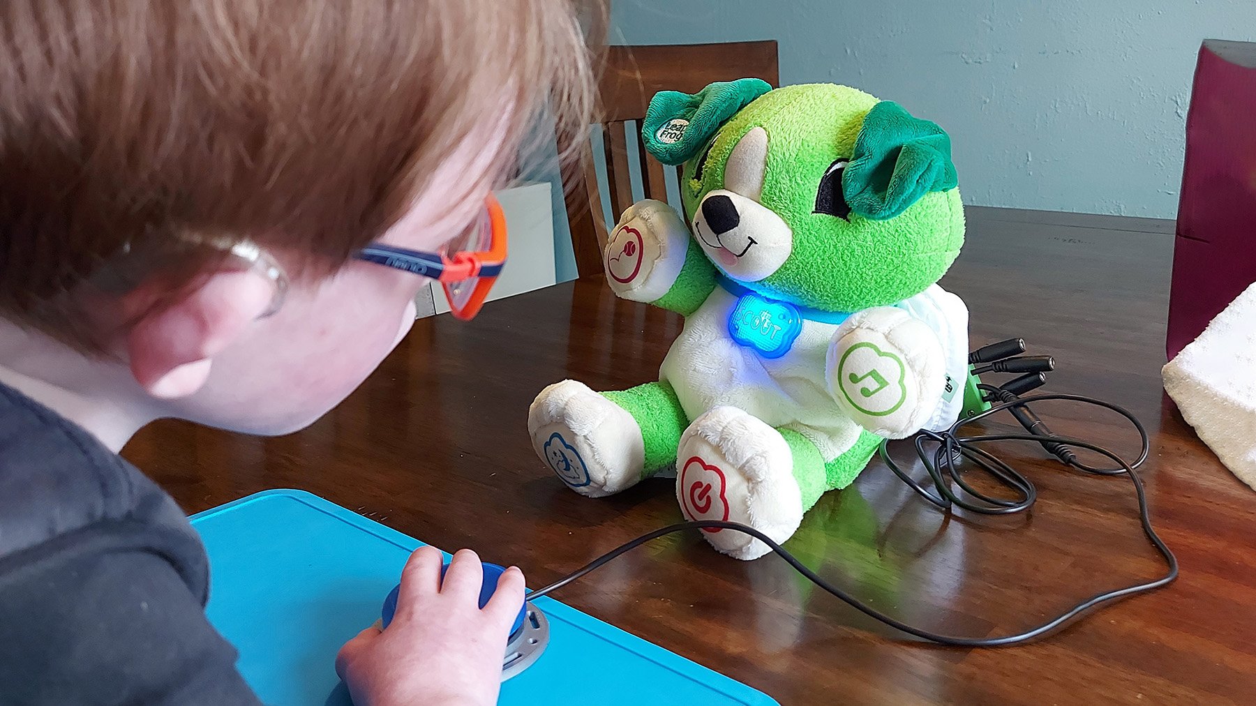 A young boy playing with a green toy dog.