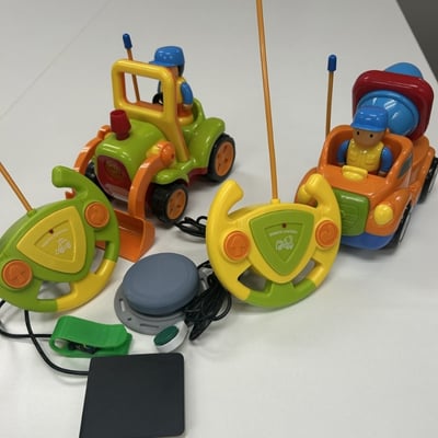 Two sets of remote control cars with controllers that each have two switches plugged in