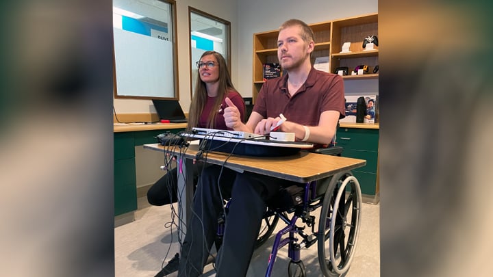 A man in a wheelchair and a woman looking at a camera off screen