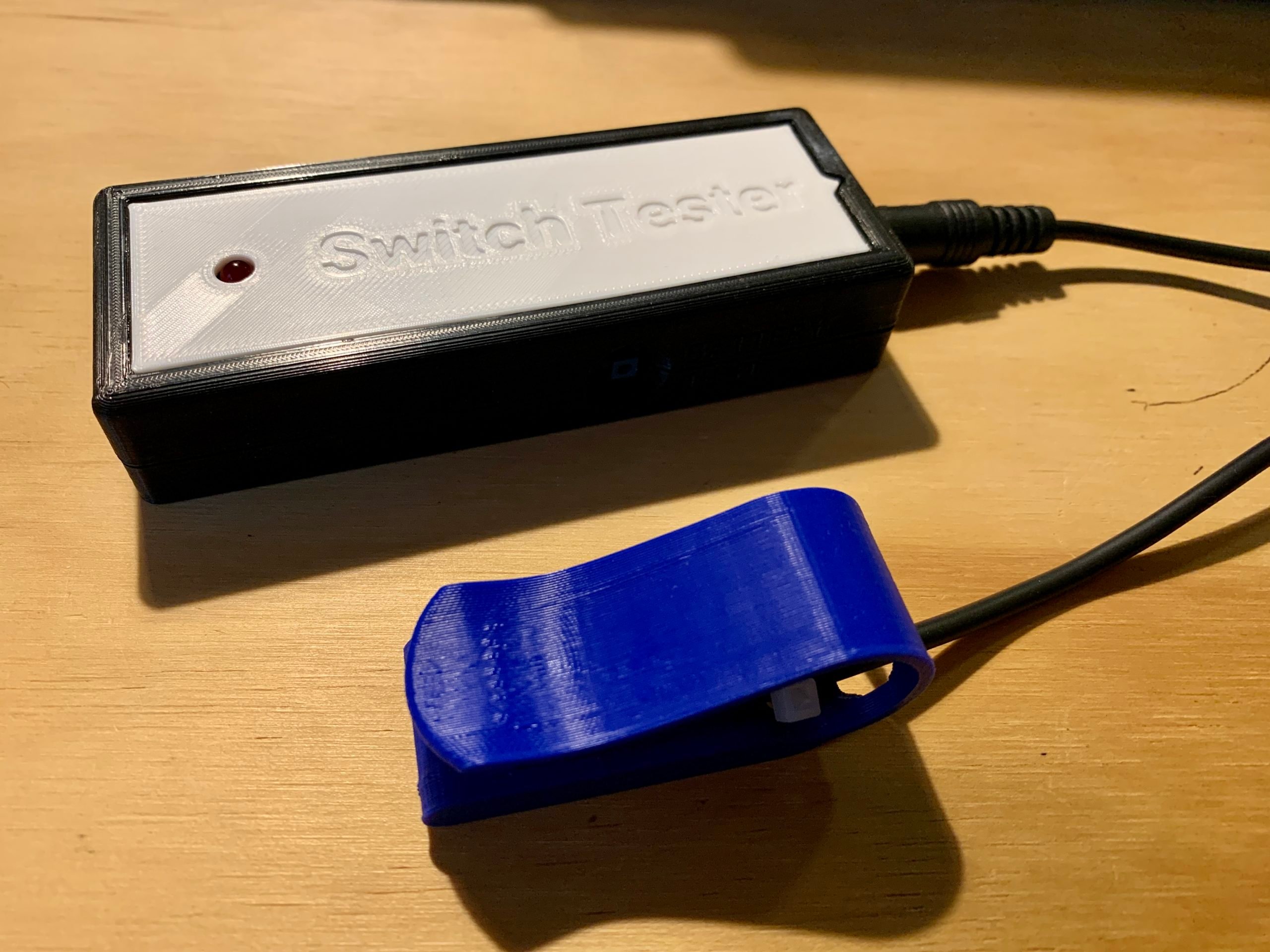 A blue 3d printed solderless switch plugged into a black and white switch tester.
