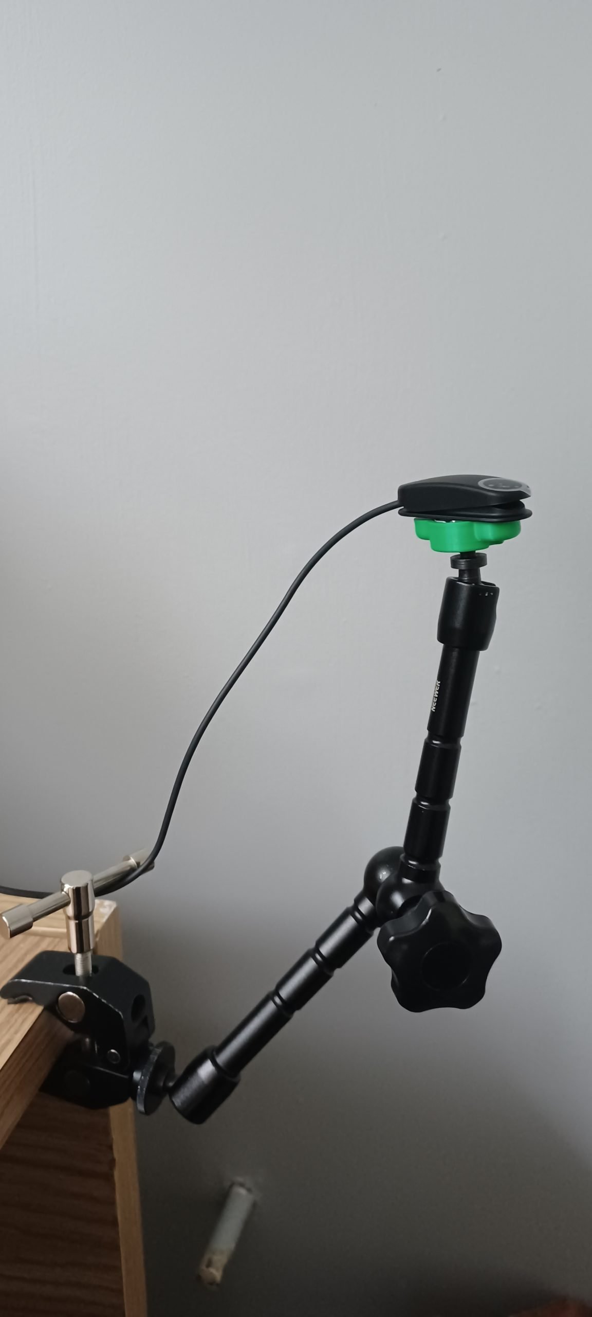 A green 3d printed mounting base attached to a black Logitech large button