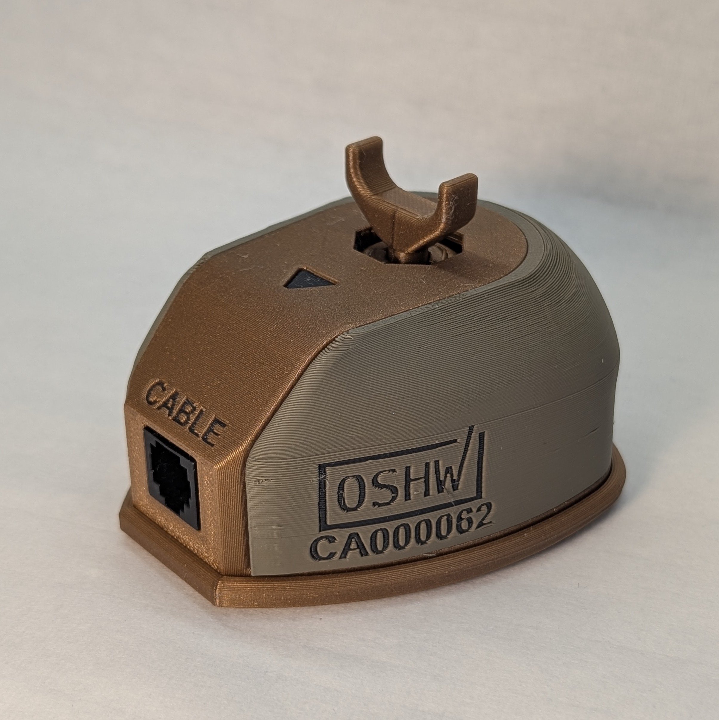 The back side of the Willow Joystick, showing the cable connection, orientation label, and OSHW certification number. The base of the joystick is printed in gold, and the shell is printed in green. The joystick is using the large goalpost topper.