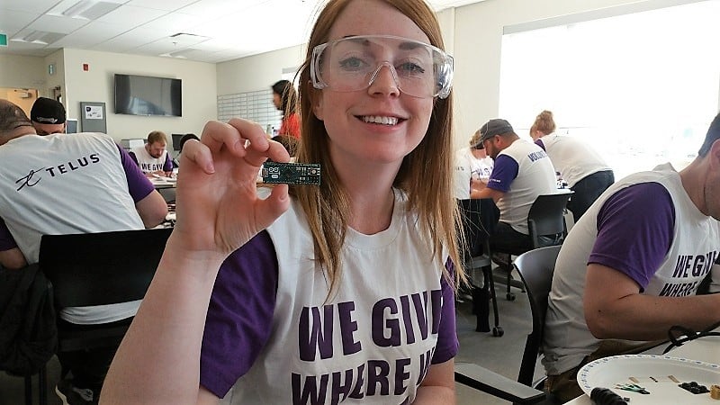 A Telus staff holding up a circuit board.
