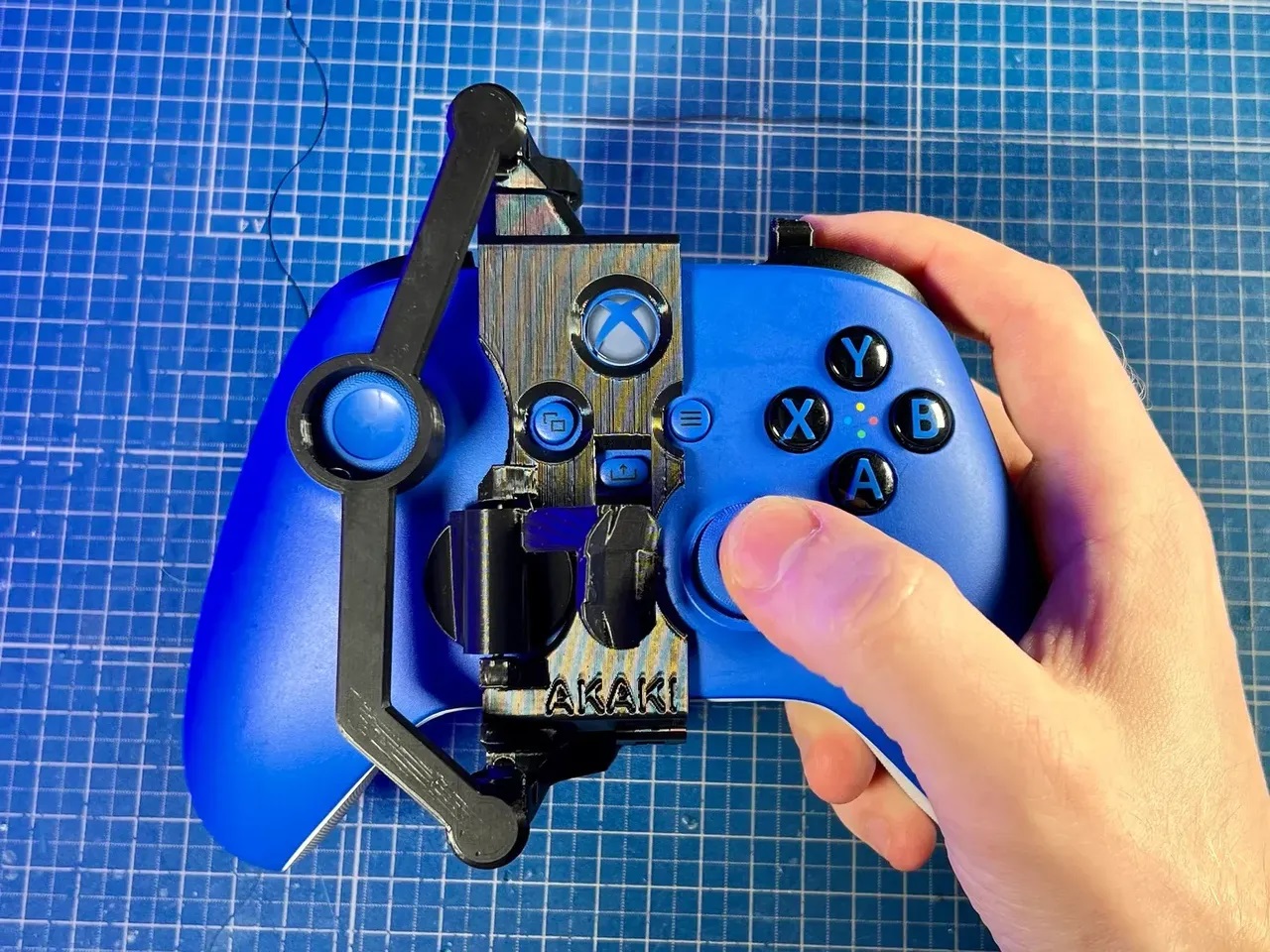 A one-handed controller modification on a blue Xbox Series X|S Controller. This controller modification is 3D printed in black and is the right-handed variation.