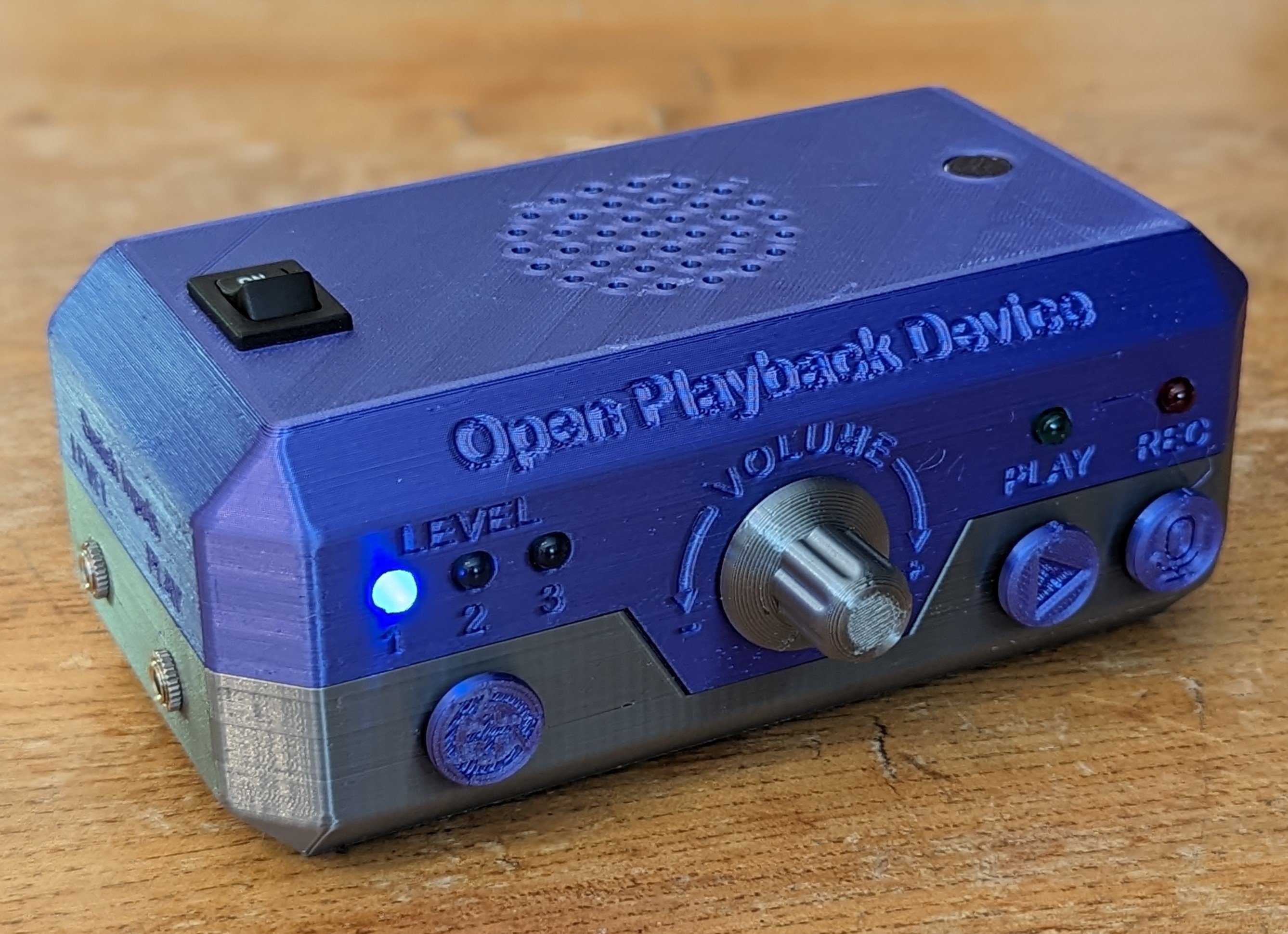A blue and grey 3D printed Open Playback Recorder. On the front are 5 LEDs, 1 knob in the center, and 3 push buttons.