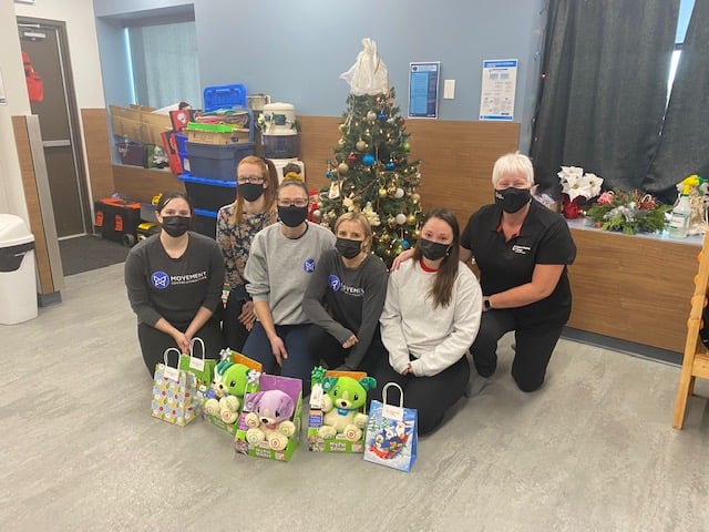Volunteers with their assistive devices kneeling down around a Christmas tree.