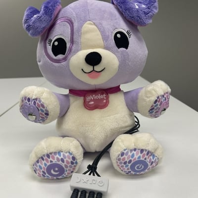 A plush toy shaped as a dog with a collar that says violet and a 3D printed cable clamp containing four mono cables