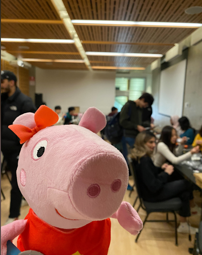 Close-up of Peppa Pig with students working in the background