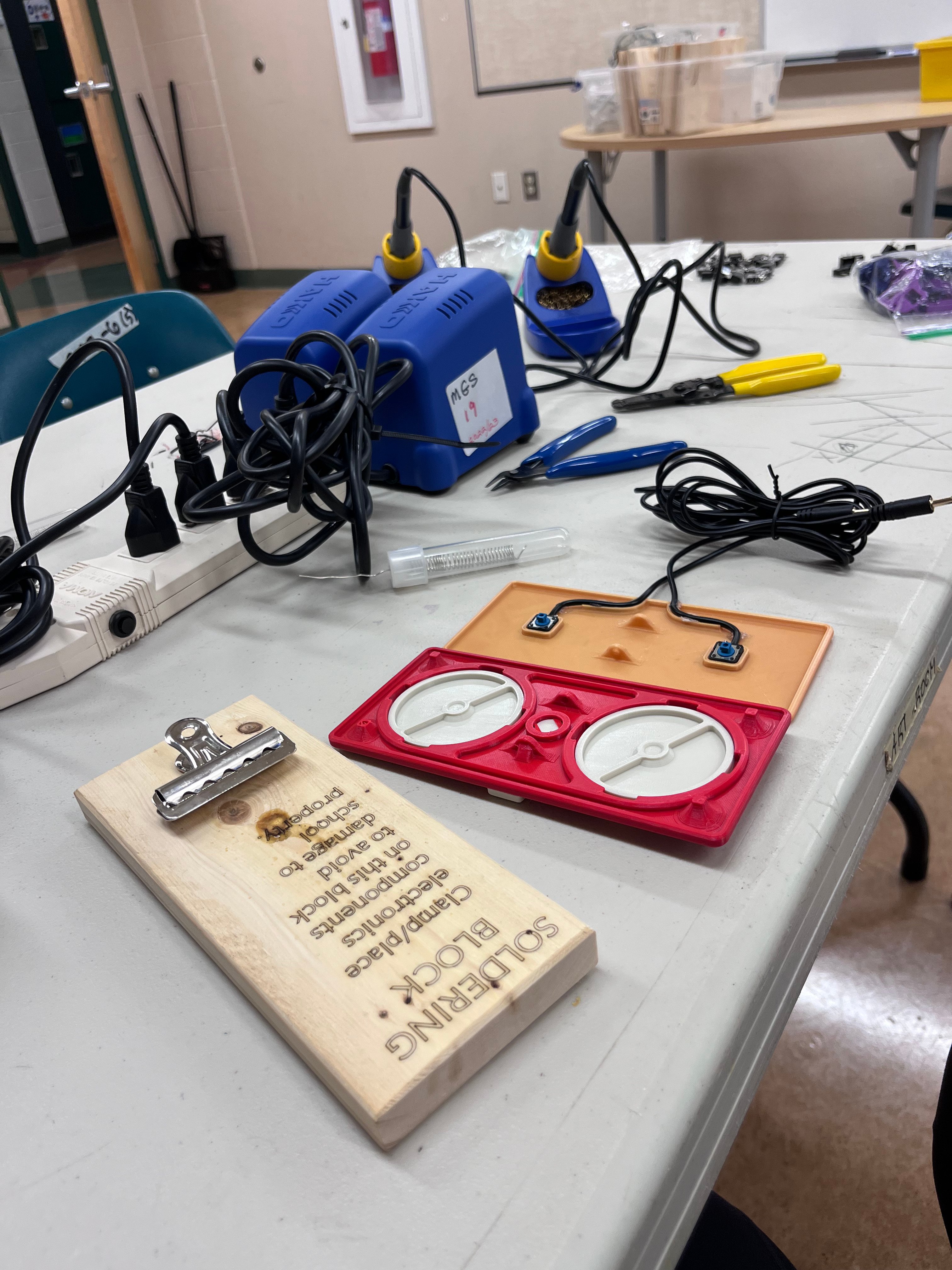 A rocker switch and soldering irons on a table