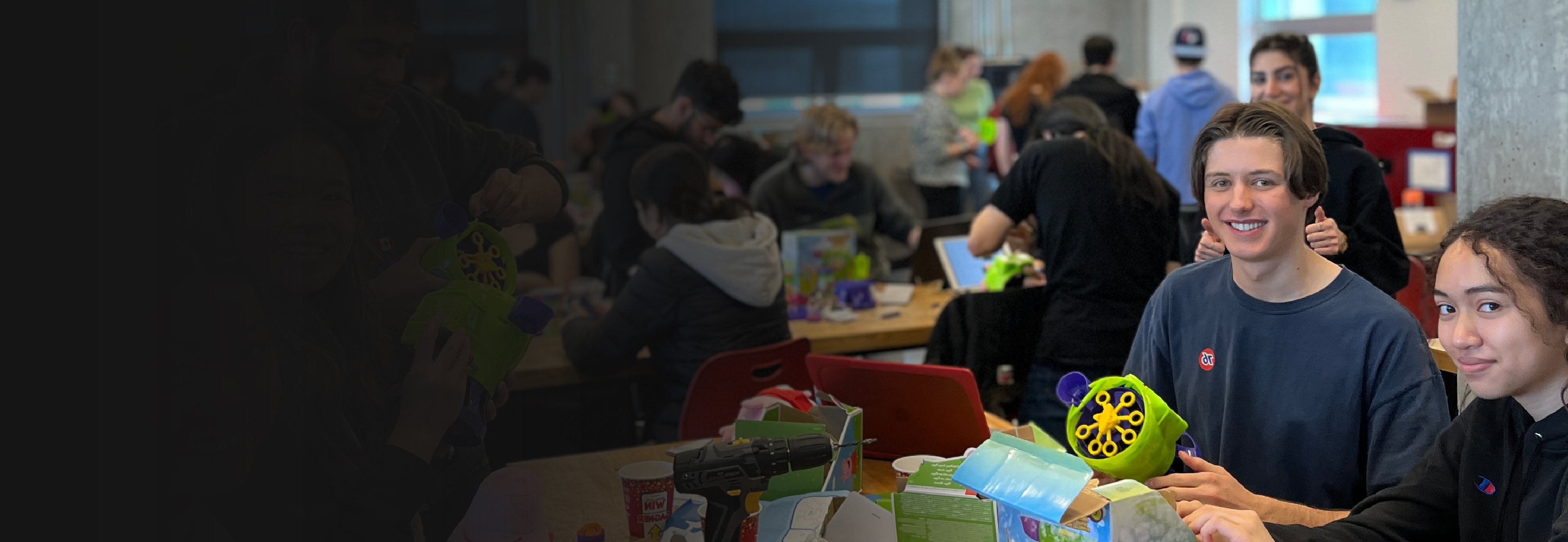 University students sitting at a workbench adapting toys.