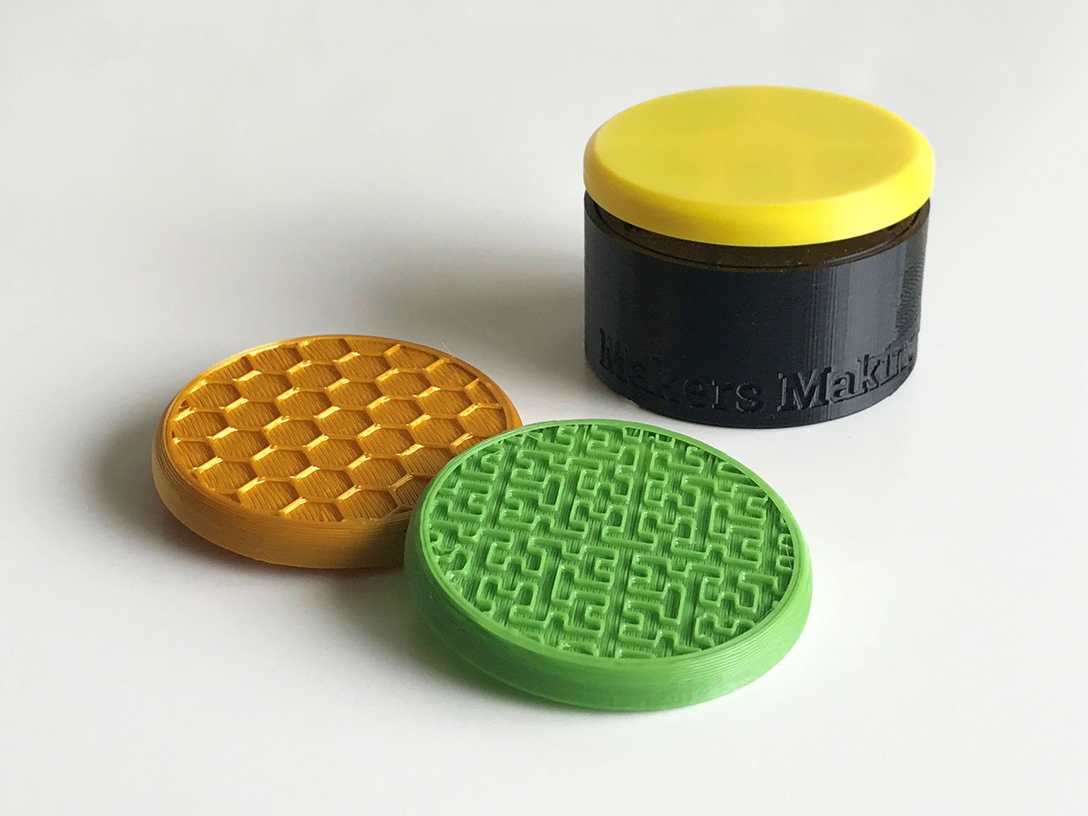 A yellow and black 3d printed assistive switch behind a gold and green switch top.