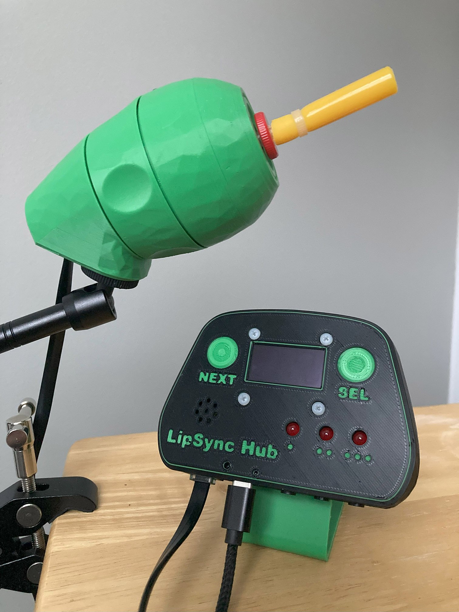 A green 3D printed LipSync joystick and Hub on a table