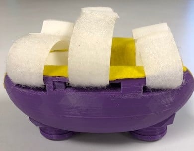 Picture of a 3d printed arm skate with yellow felt lining and white hook and loop straps.