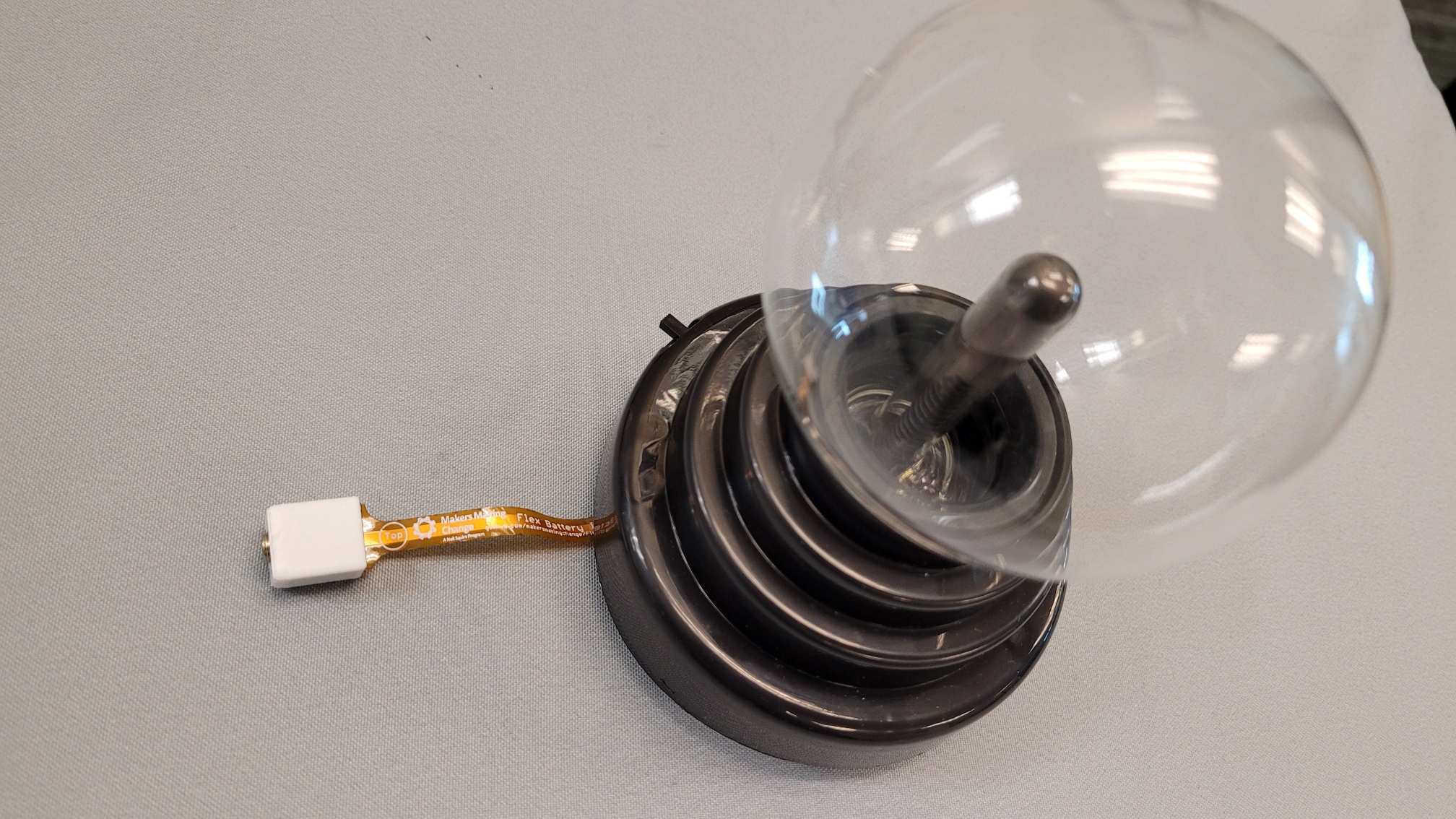 An orange and white battery interrupter installed in a switch adapted plasma globe toy.