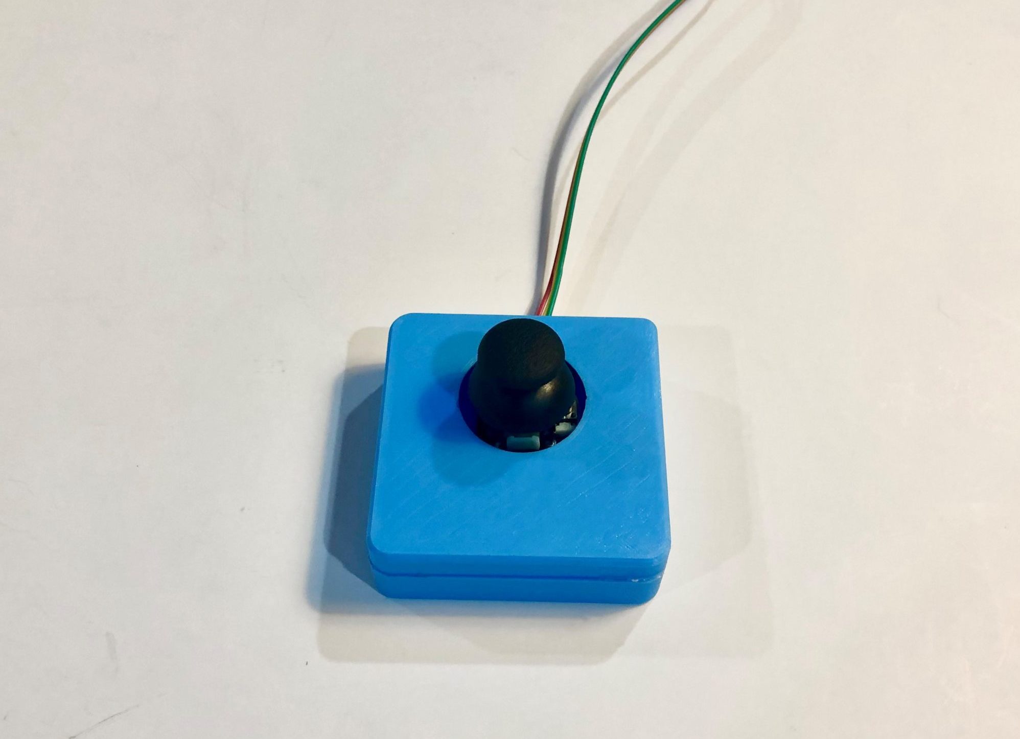 A rectangular 3d printed analog thumbstick on a white table.