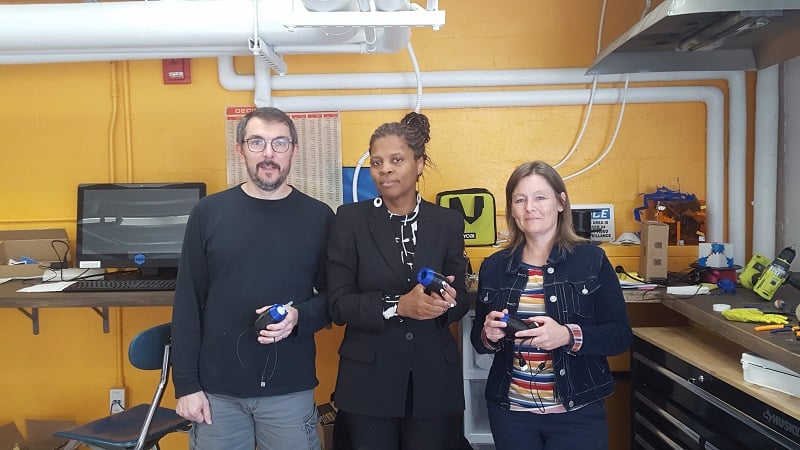 Three volunteers holding their built assistive devices at the GW Innovation Center.