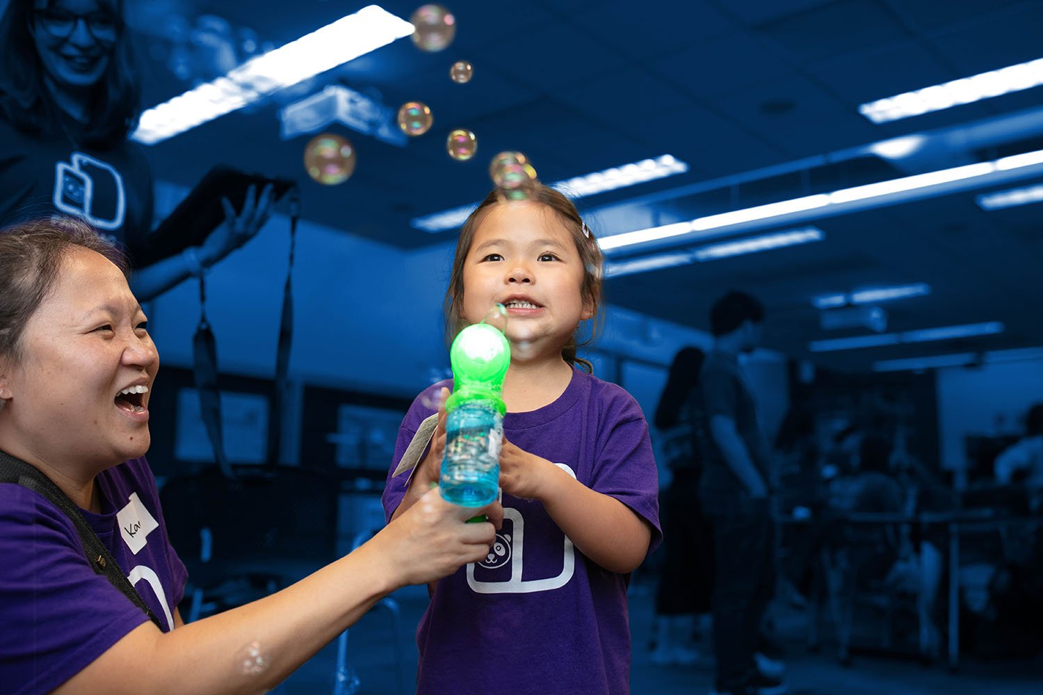 A young girl using an adapted bubble blower.