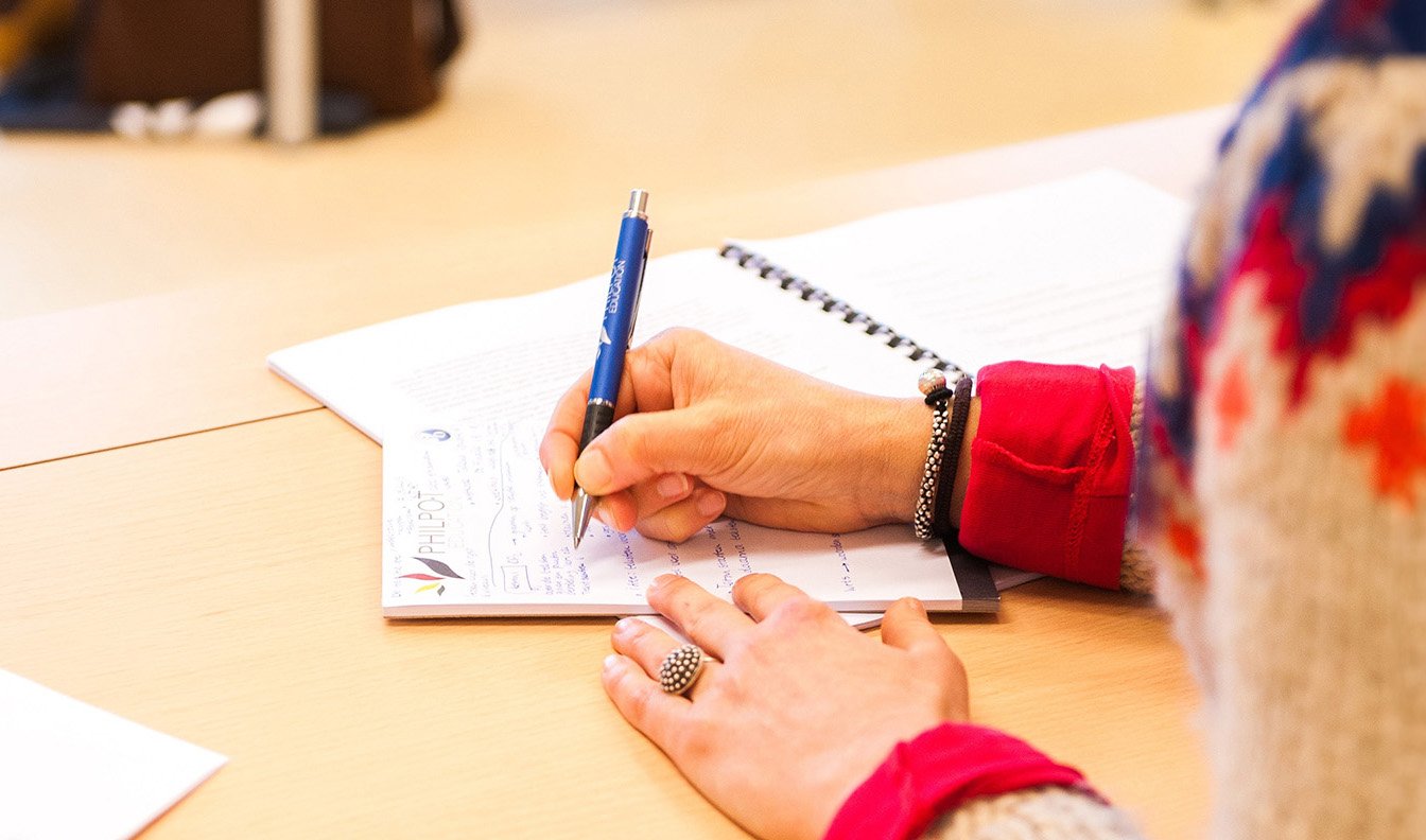A teacher writing notes on a piece of paper.