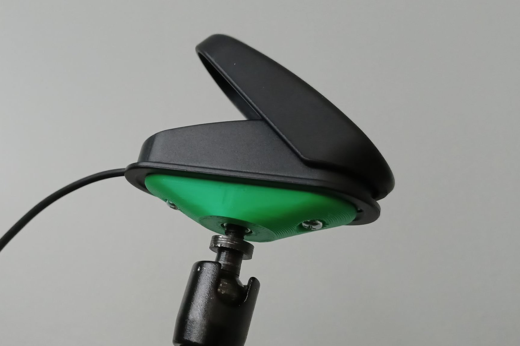 A green 3d printed mounting base attached to a black logitech variable trigger button.