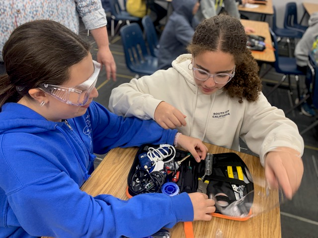 Two girls examining a soldering kit.
