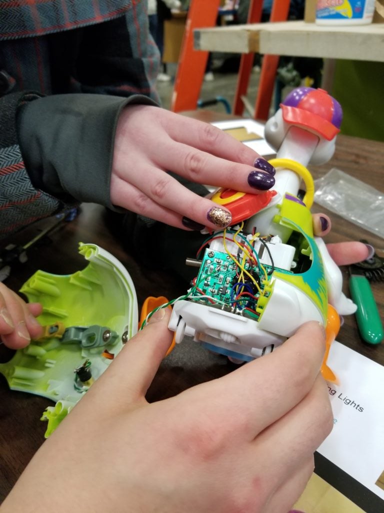 A hand hovering over an exposed assistive device showing the internal electronics.
