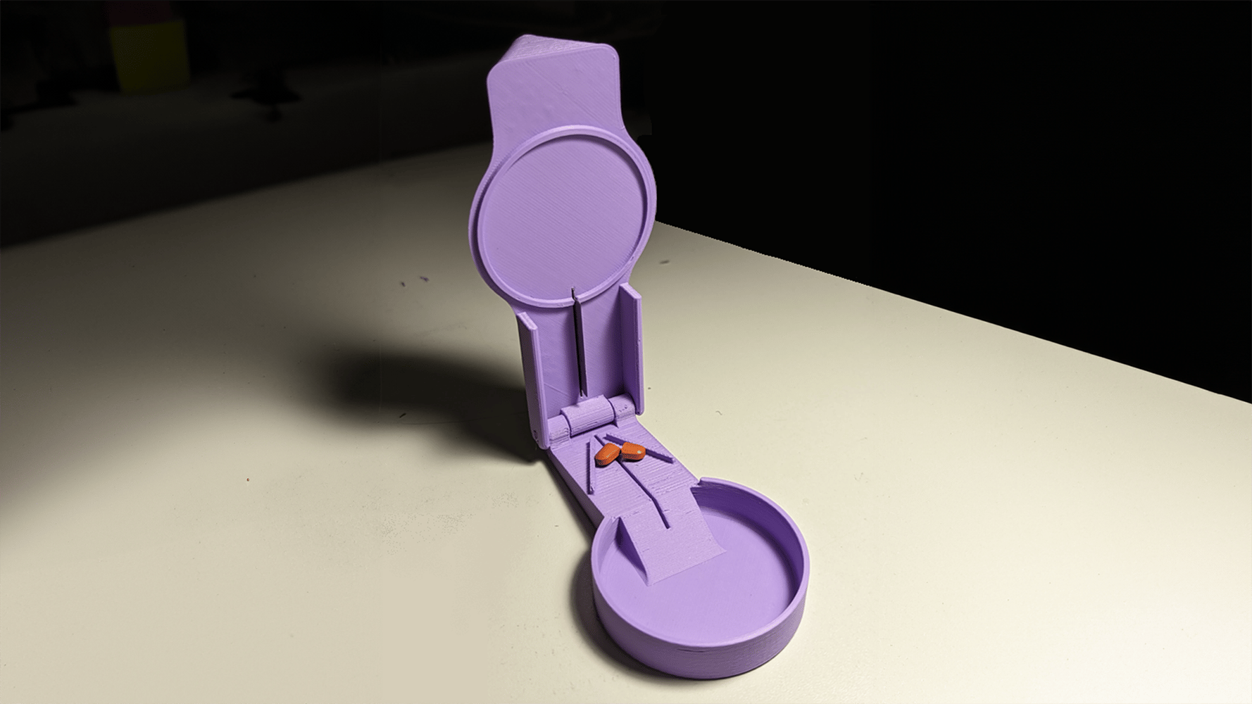 Pill splitter in the open position with a pill inside that has be cut into 2 pieces