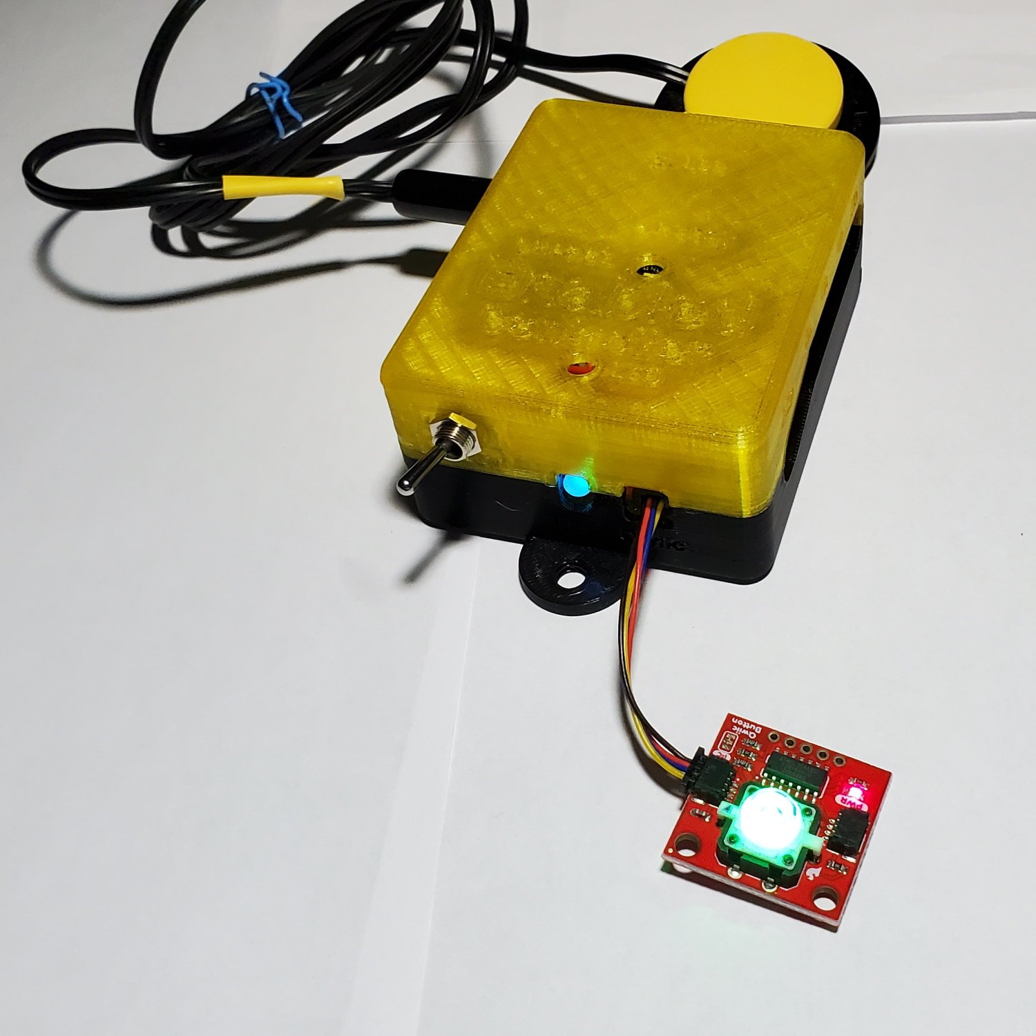 A yellow and black 3d printed enabled controller and a red PCB with a green LED lit up.