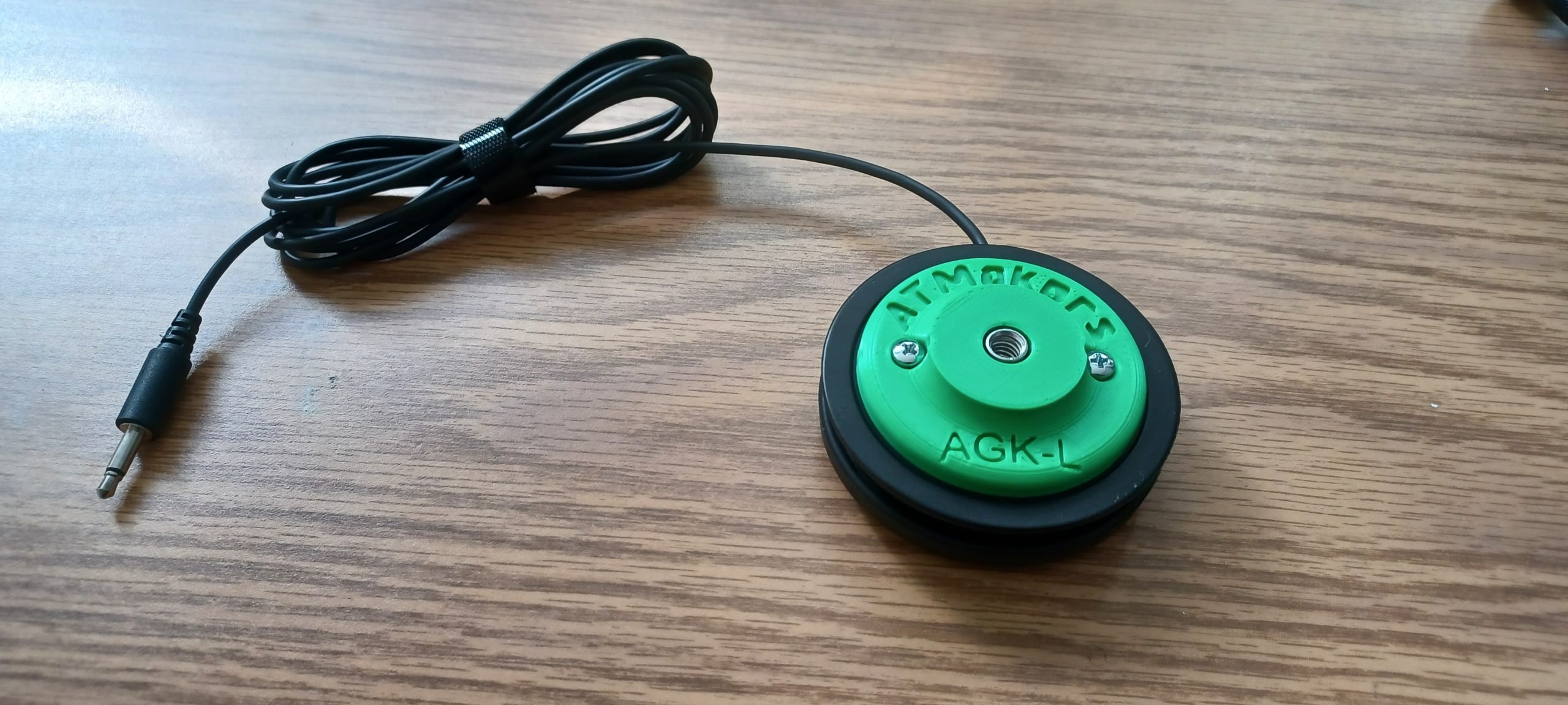 A green 3d printed adapted attached to Logitech's large gaming button.