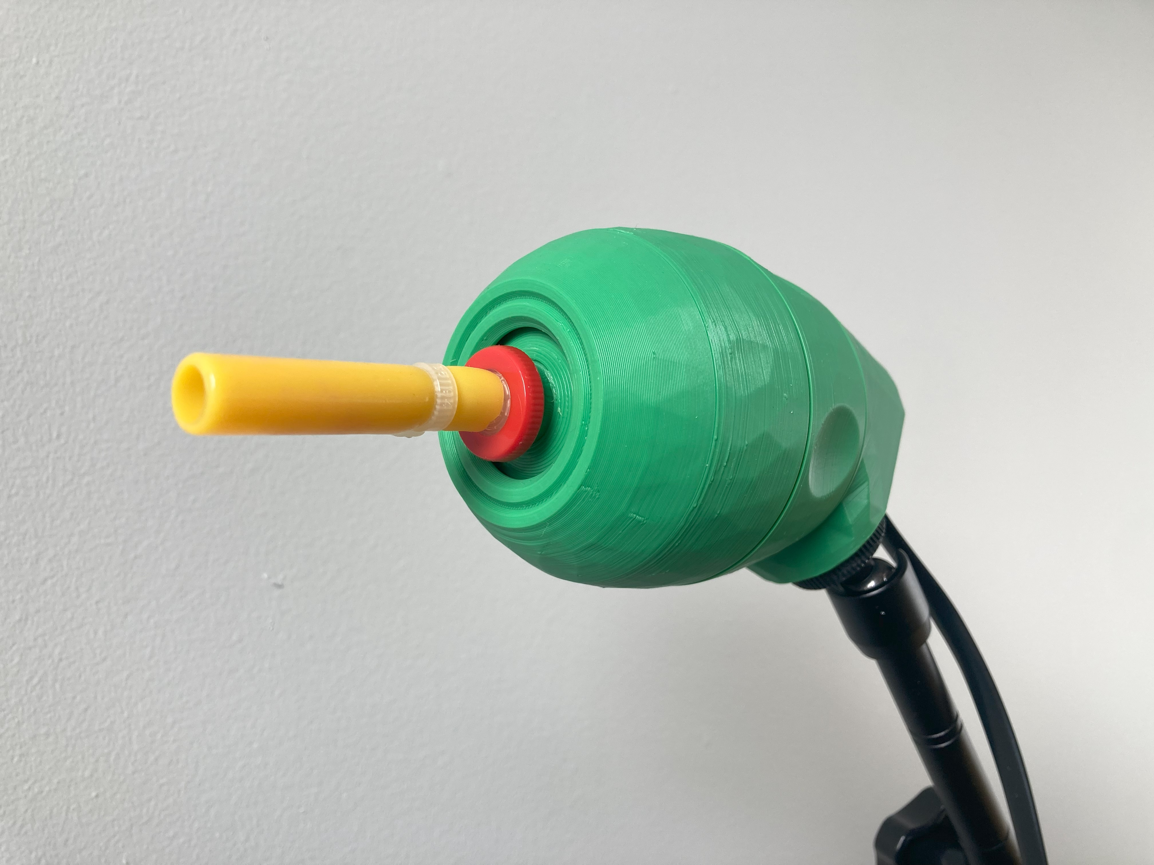 A green 3d printed lipsync joystick with a yellow mouthpiece
