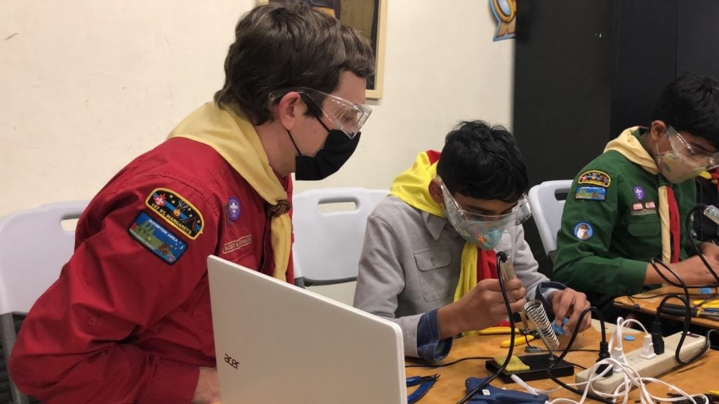 Three volunteers building assistive tech at an event in Fredericton.