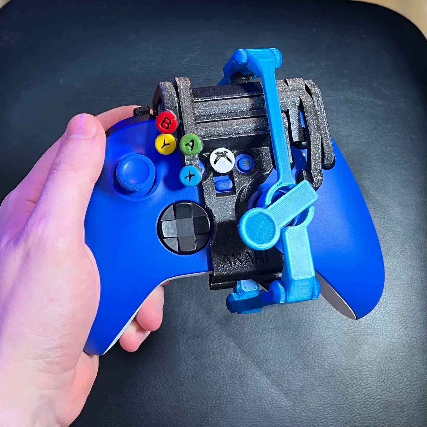 A one-handed controller modification on an Xbox Series X|S Controller. This controller modification is 3D printed in black and blue and is the left-handed variation.