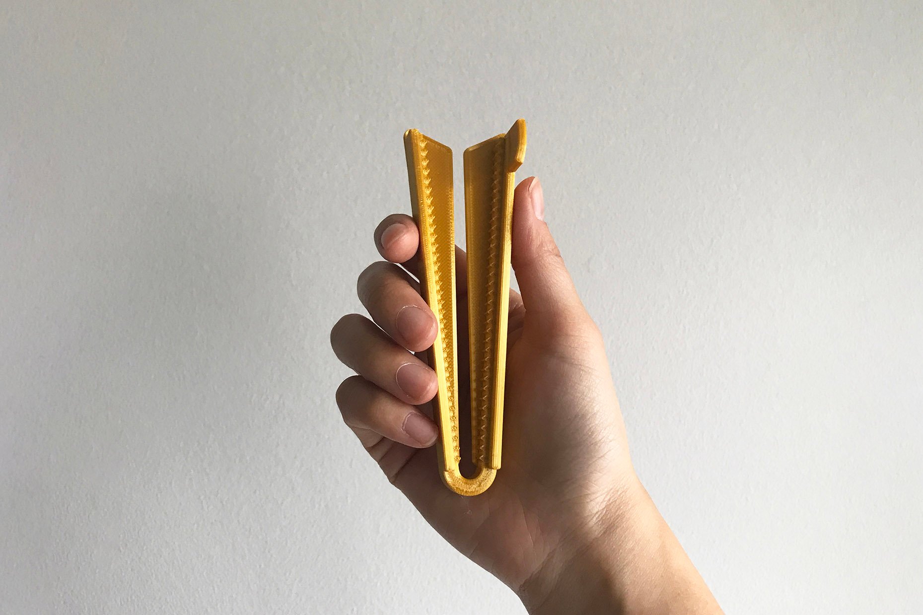 A hand holding a tube opener