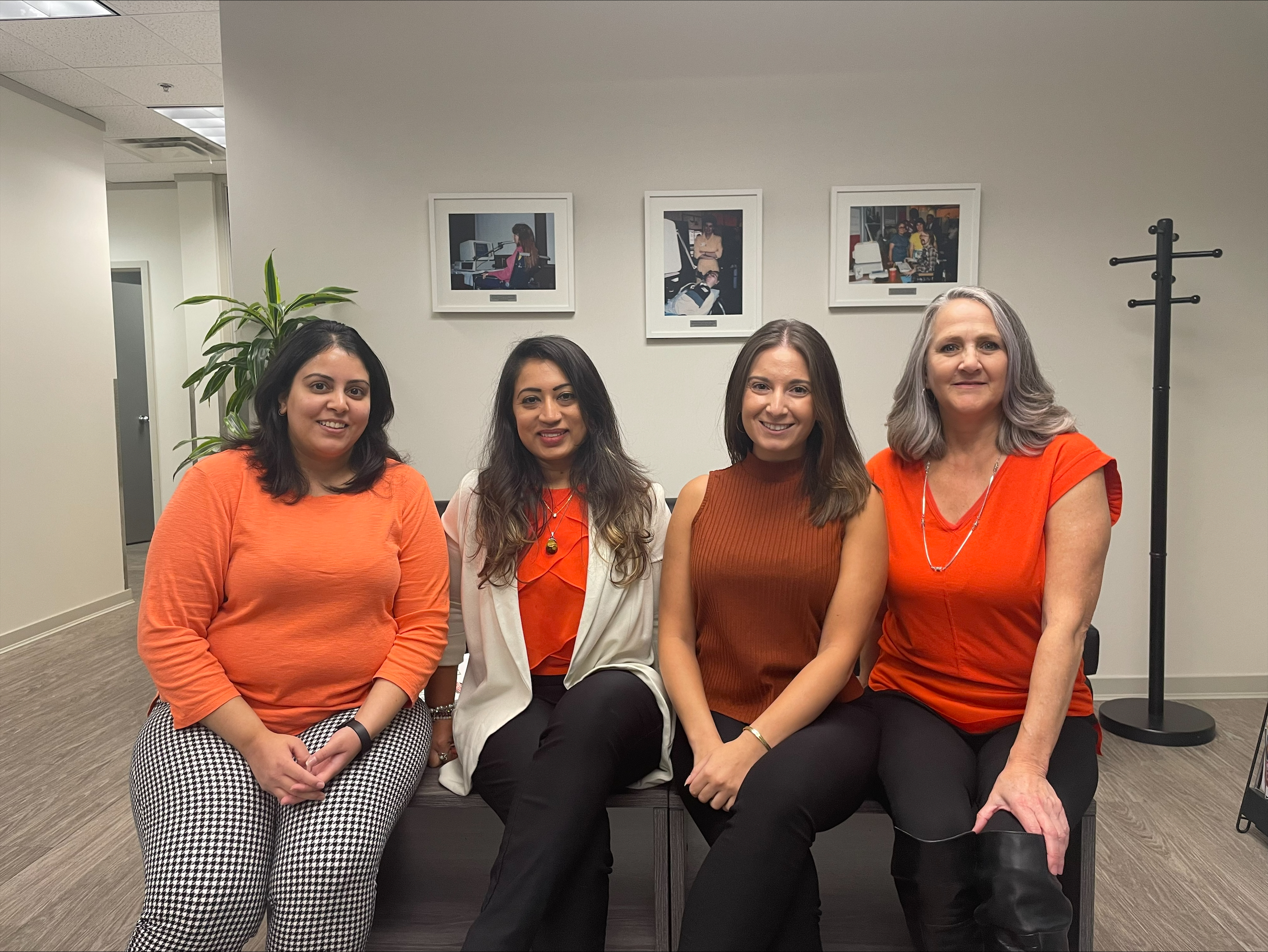 Four Neil Squire staff wearing an orange shirt in the office lobby.
