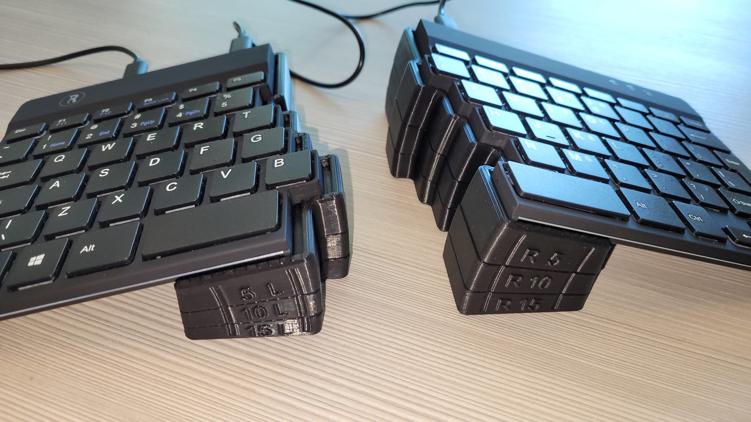 A picture of an R-Go Split Ergonomic Keyboard resting on 3D Printed blocks forming a 15-degree tenting angle.
