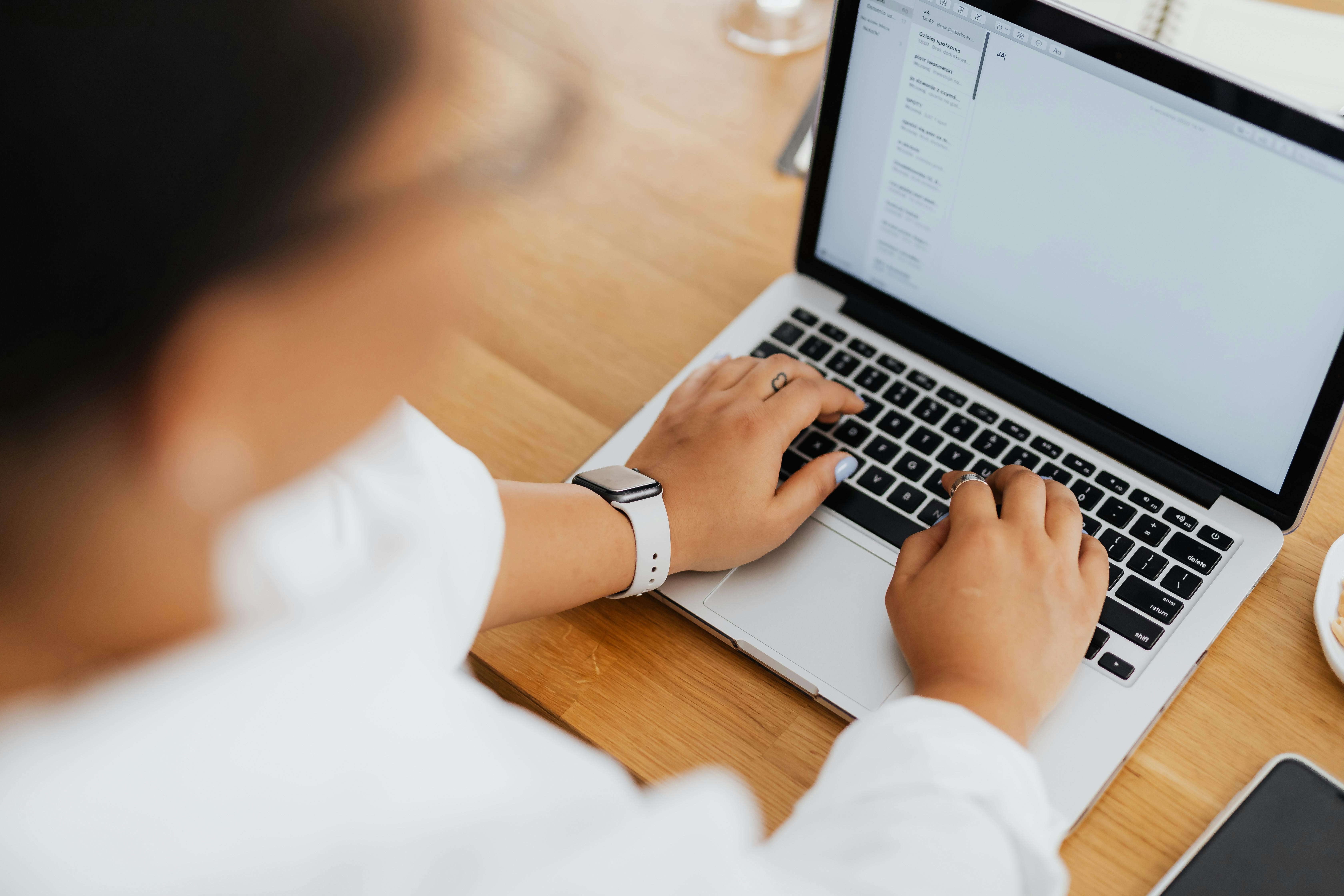 A person with their hands on a laptop keyboard.
