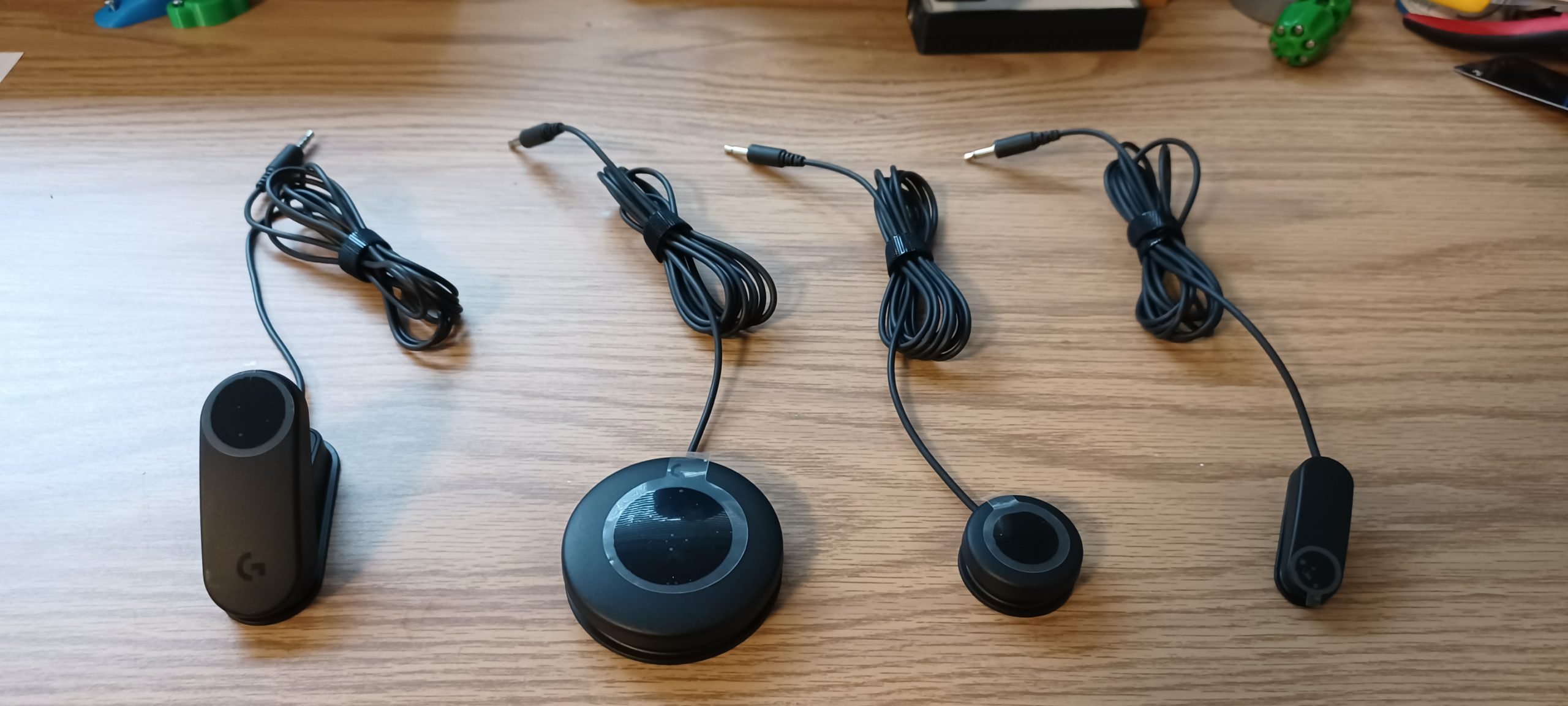 Four black assistive switches from the Logitech Adaptive Gaming Kit on a wooden background.