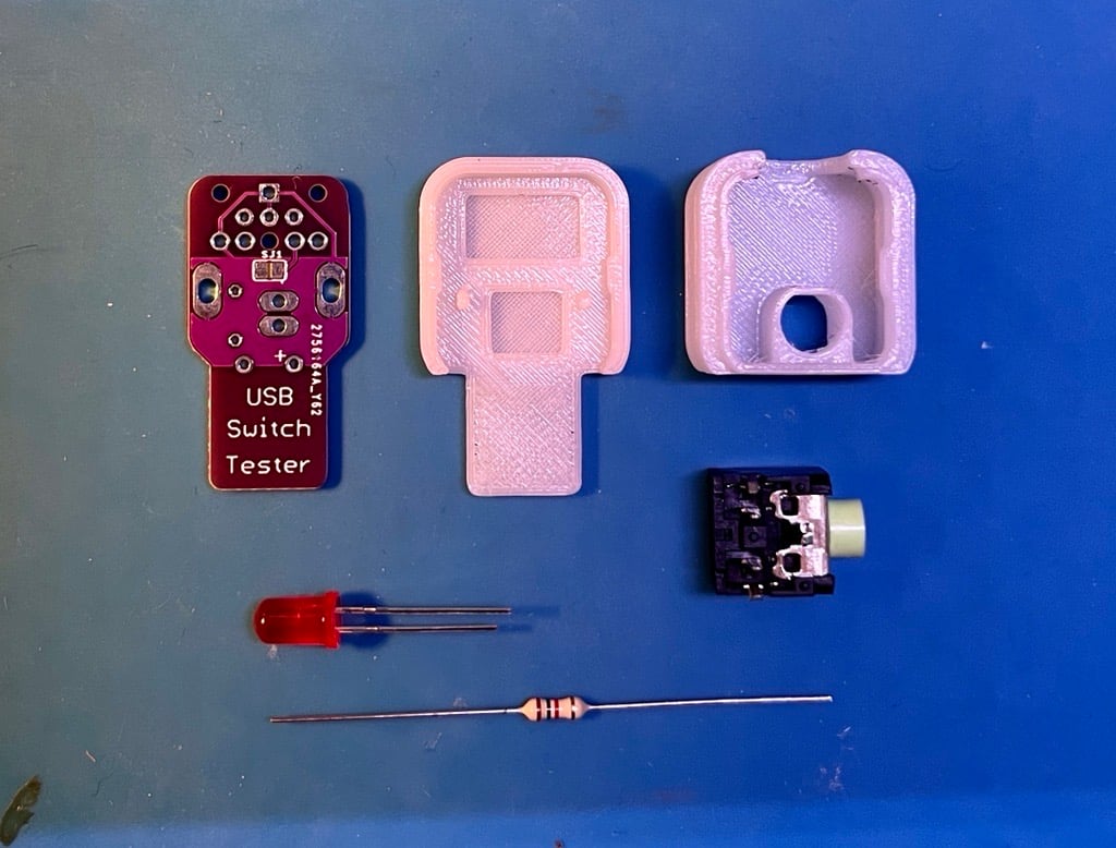 3D printed and electronic components of the USB Switch Tester laid out on a blue table.