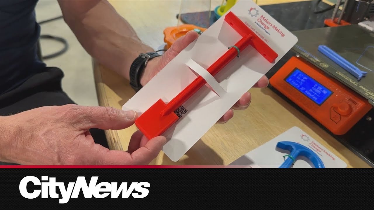 A hand holding up a red 3d printed seat belt remover in a packaging