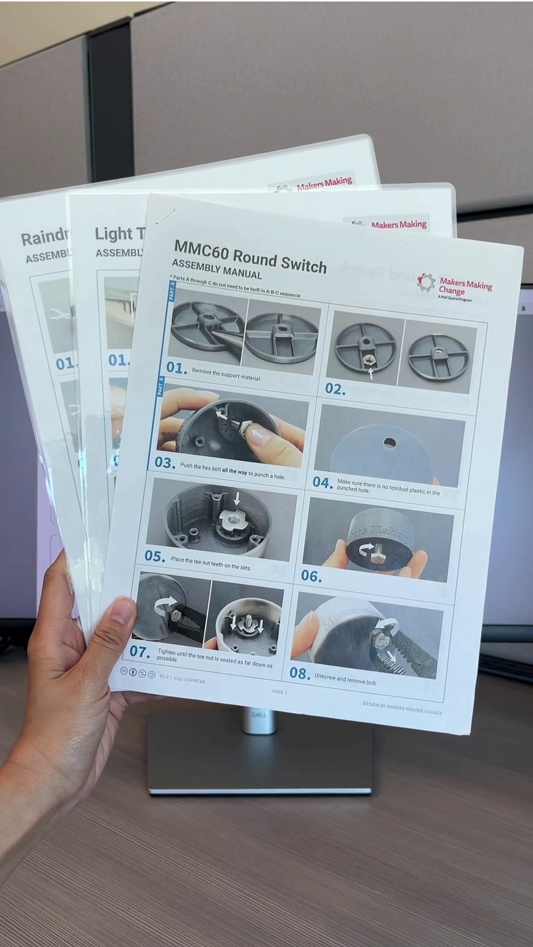A hand holding up three assembly instructions for the MMC60 Round Switch