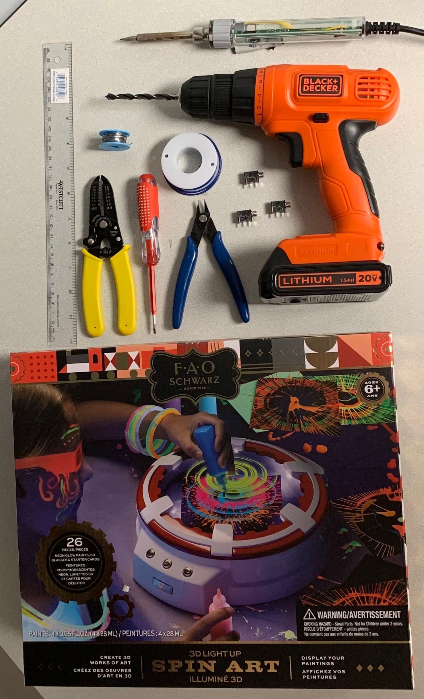 Various hand tools, an soldering iron, and electronic parts on a white table.