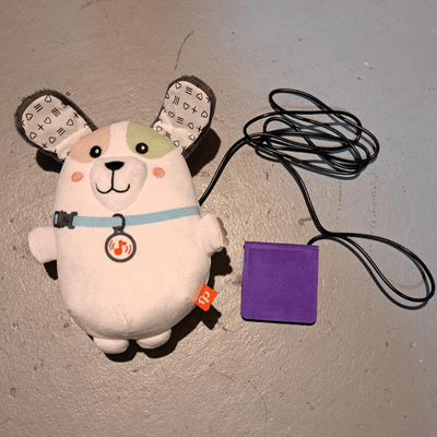 Soft white puppy plush toy with a purple switch plugged in.