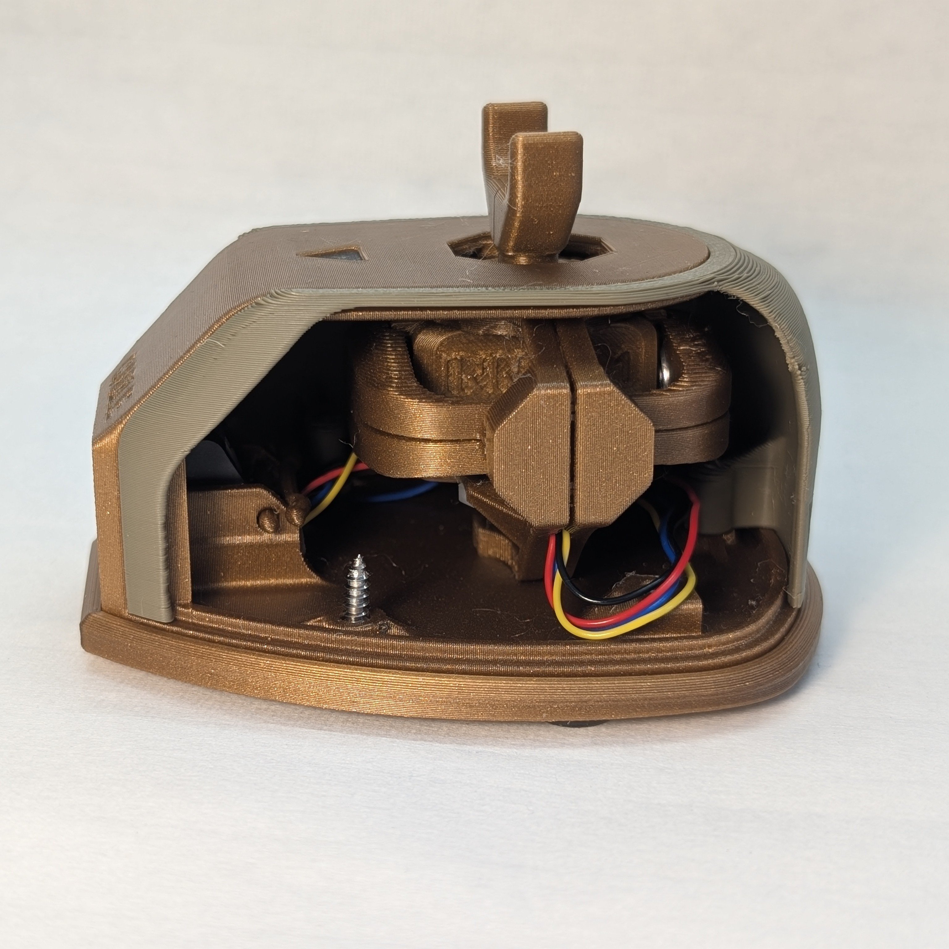 A side view of the willow joystick with a cutaway shell that shows the internal gimbal. The joystick base and gimbal are printed in gold, with the shell in green. The joystick is using a large goalpost topper and is on a white background.