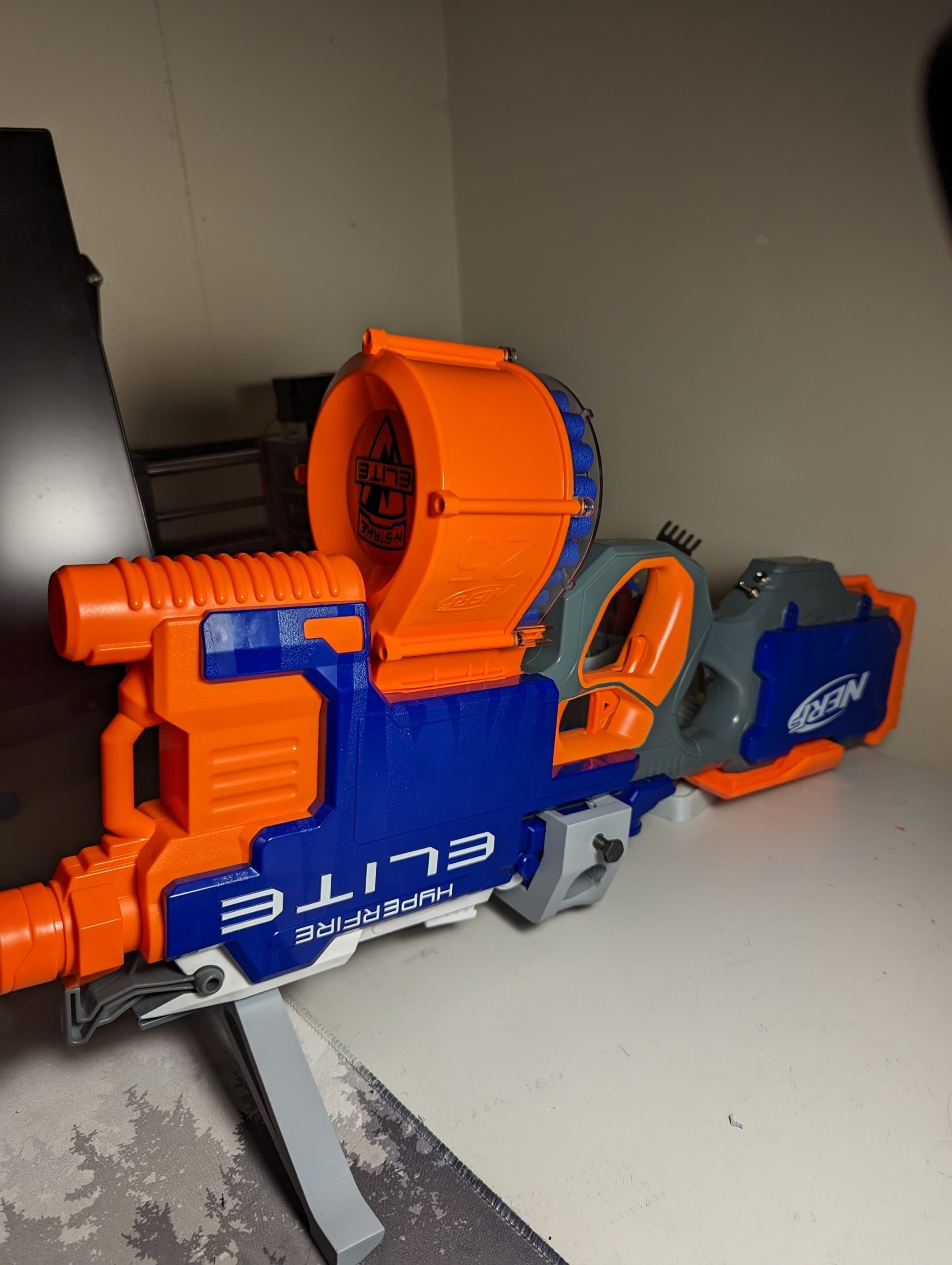 A blue and orange switch-adapted nerf gun on a white table.