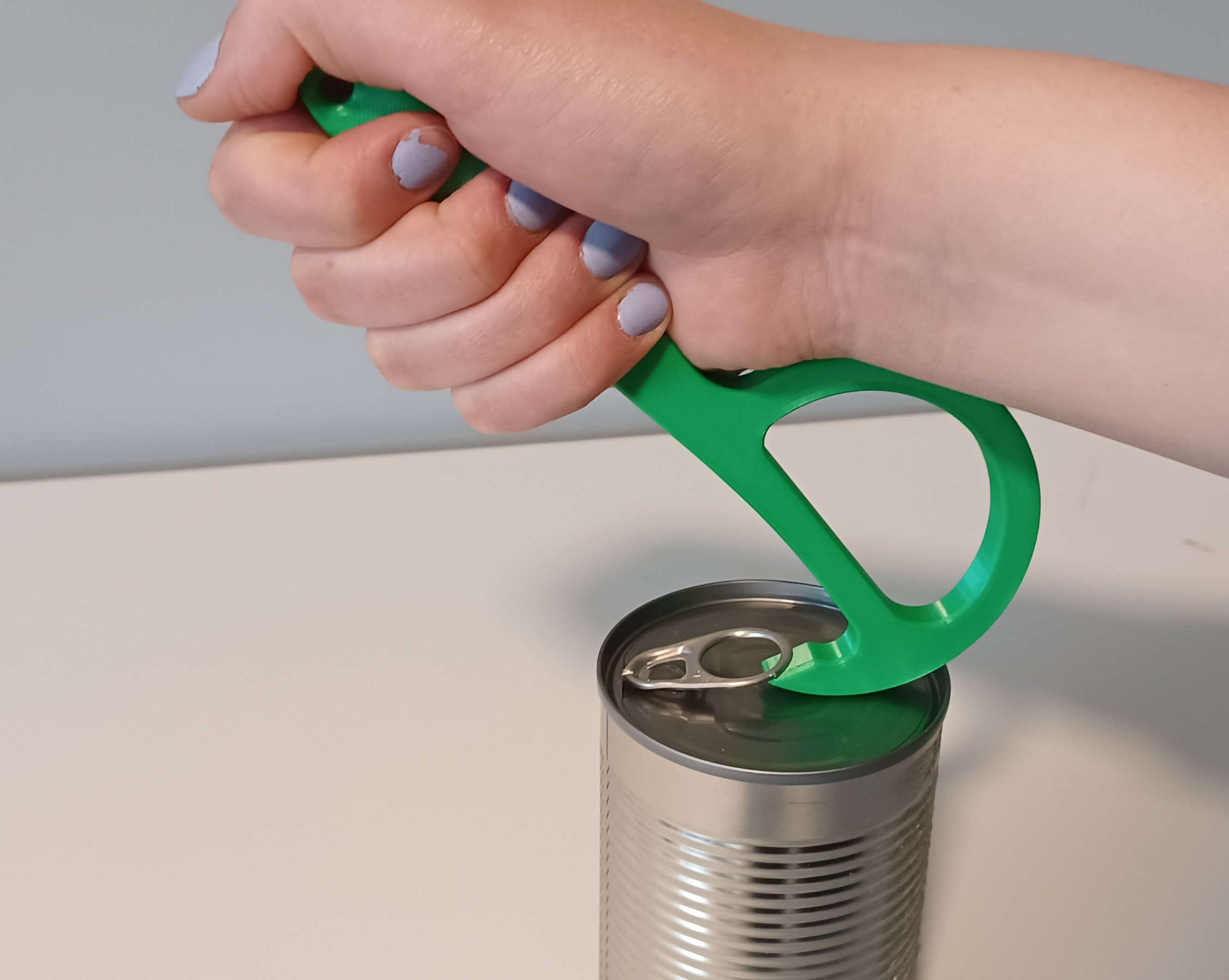 A hand placing the 3d printed pull-tab can opener under a pull-tab.
