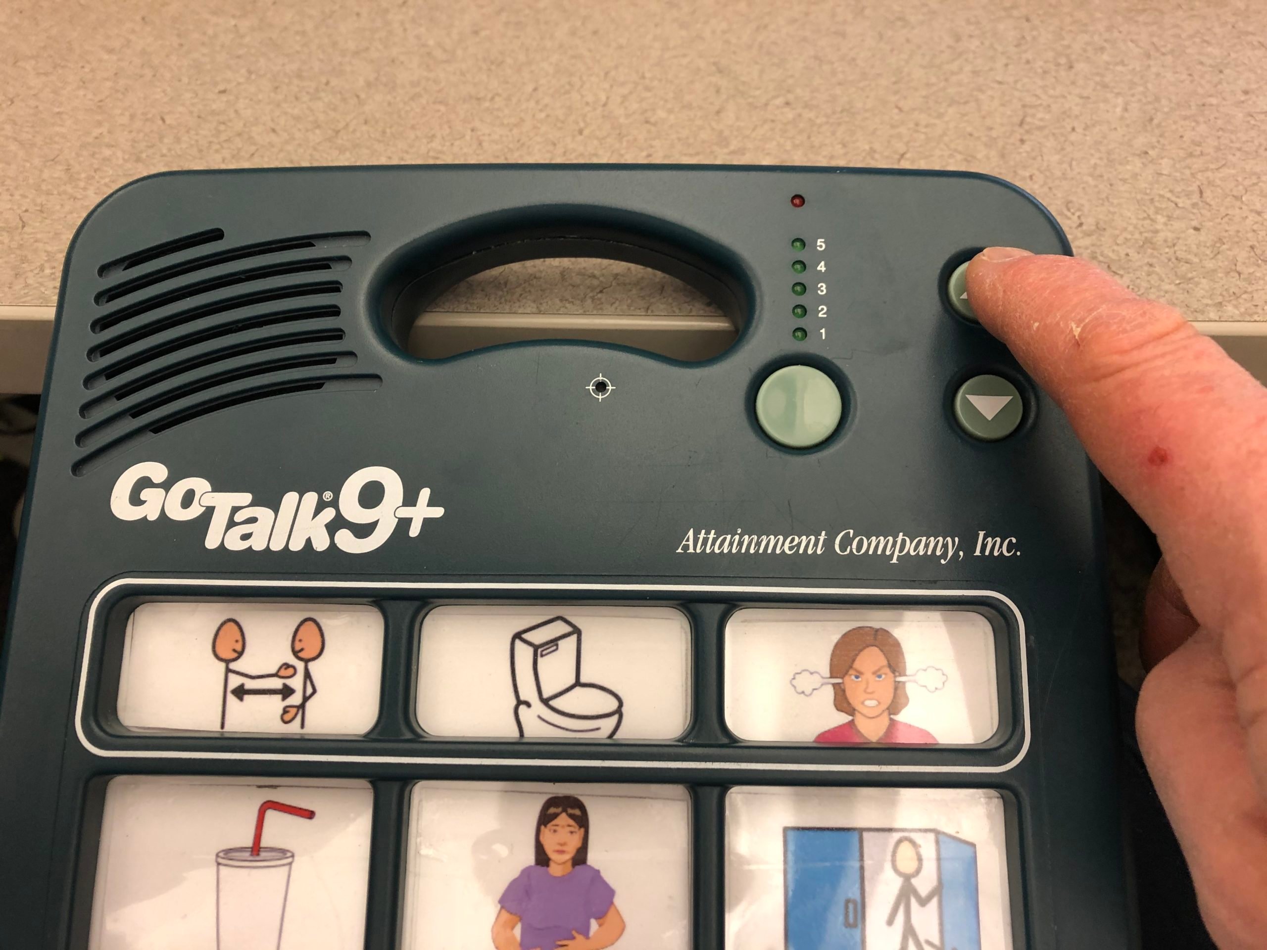 Picture of a Go Talk 9+ device with a user pressing the button with their finger
