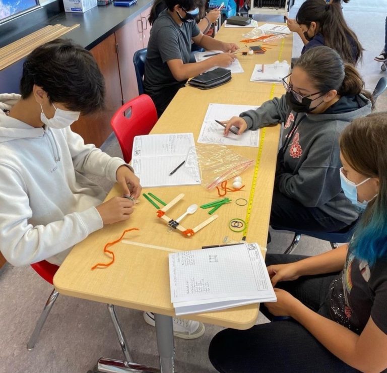 Two students building assistive technology at a table.